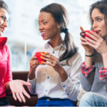 Three women in their 30s and 40s talking over coffee, supporting each other during life transitions like perimenopause."