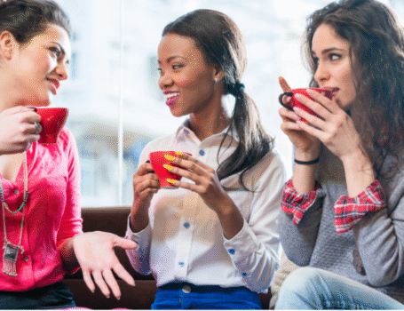 Three women in their 30s and 40s talking over coffee, supporting each other during life transitions like perimenopause."