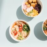 overhead shot of poke bowls on a blue surface