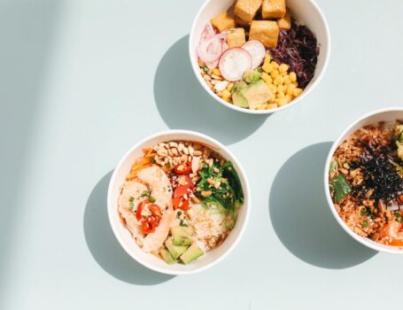 overhead shot of poke bowls on a blue surface
