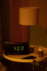 sleeping pill and digital clock on bedside table